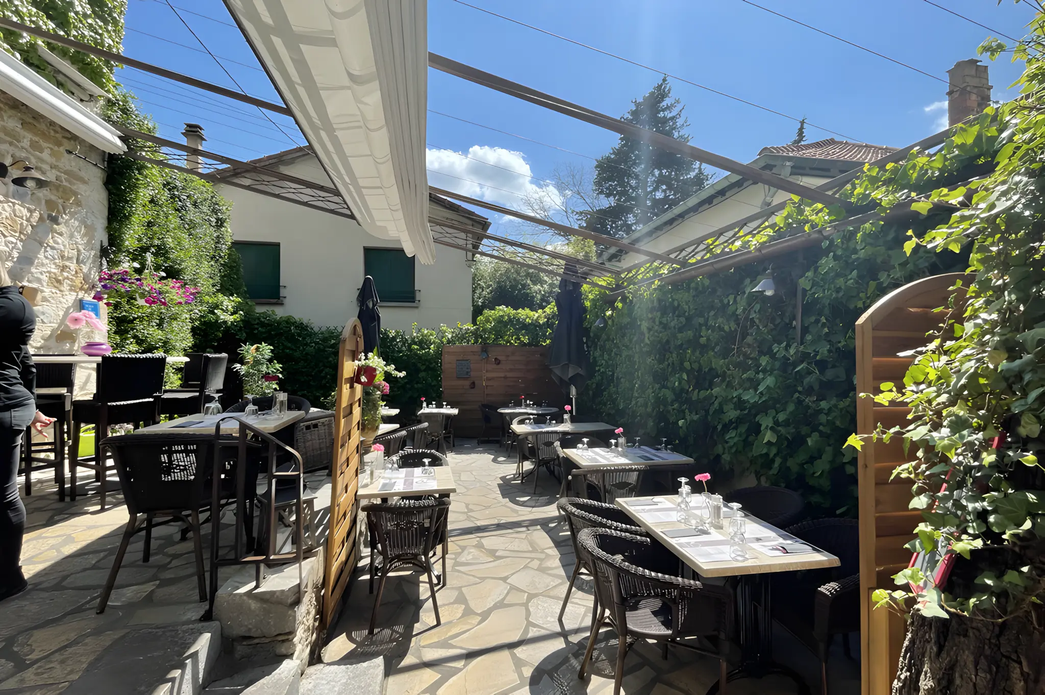 Terrasse intérieure ombragée du restaurant, pergola et verdure